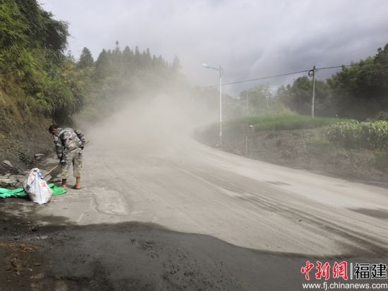 養(yǎng)路工帶上防塵口罩利用鐵鍬、竹掃把等工具清理灑落的水泥料。余思煥 攝